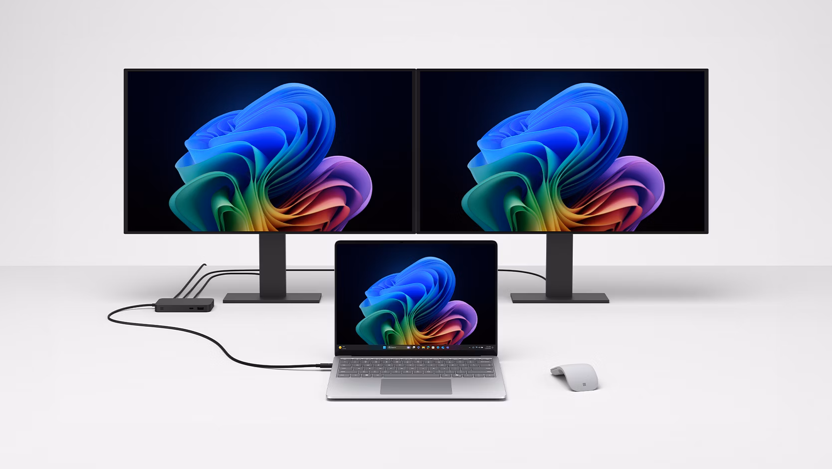 A Surface laptop is being charged by Surface USB4 Dock for Business, which also connects the laptop to two monitors in the background.