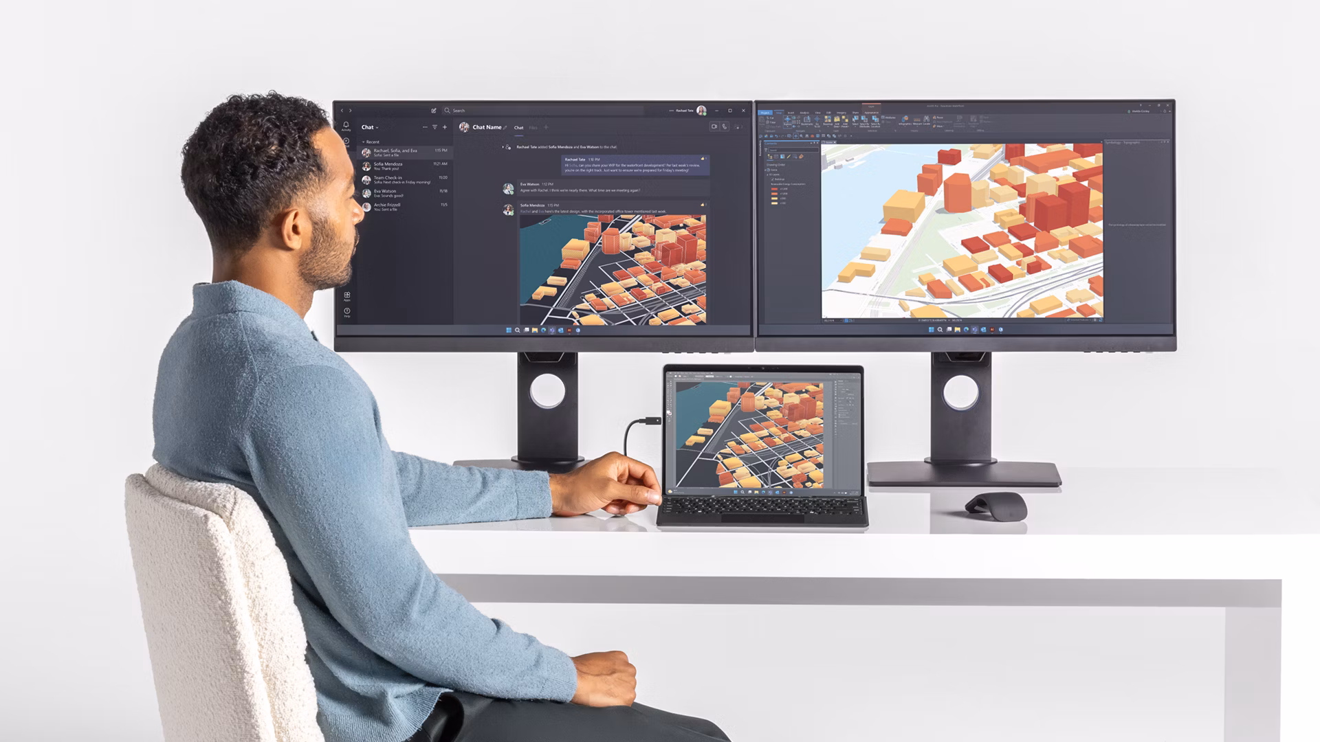 A person seated at a desk uses a docked Surface Pro to work across multiple monitors.
