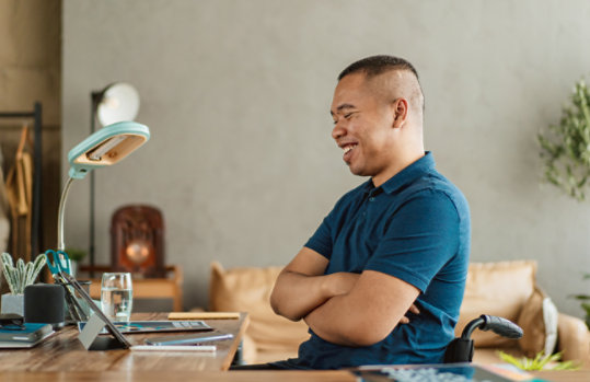 A person in a wheelchair smiles as he enjoys watching a video on a Surface device.