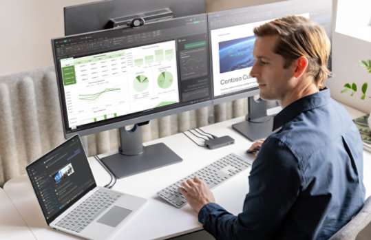 A person at a desktop setup uses a Surface Laptop for Business, Copilot+ PC , 13-inch | Snapdragon. 