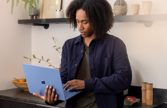 A man looks up something on his sapphire blue Surface Laptop.