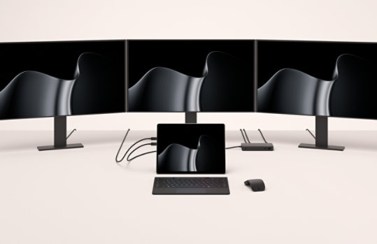 A Surface Pro for Business docked to three external monitors.