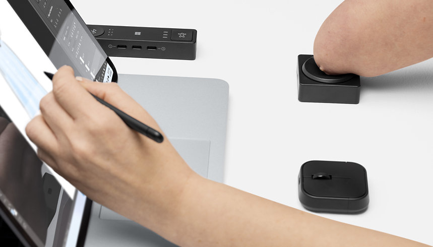 A person who has a physical disability uses Microsoft Adaptive D-pad Button and Hub with their Surface device. 